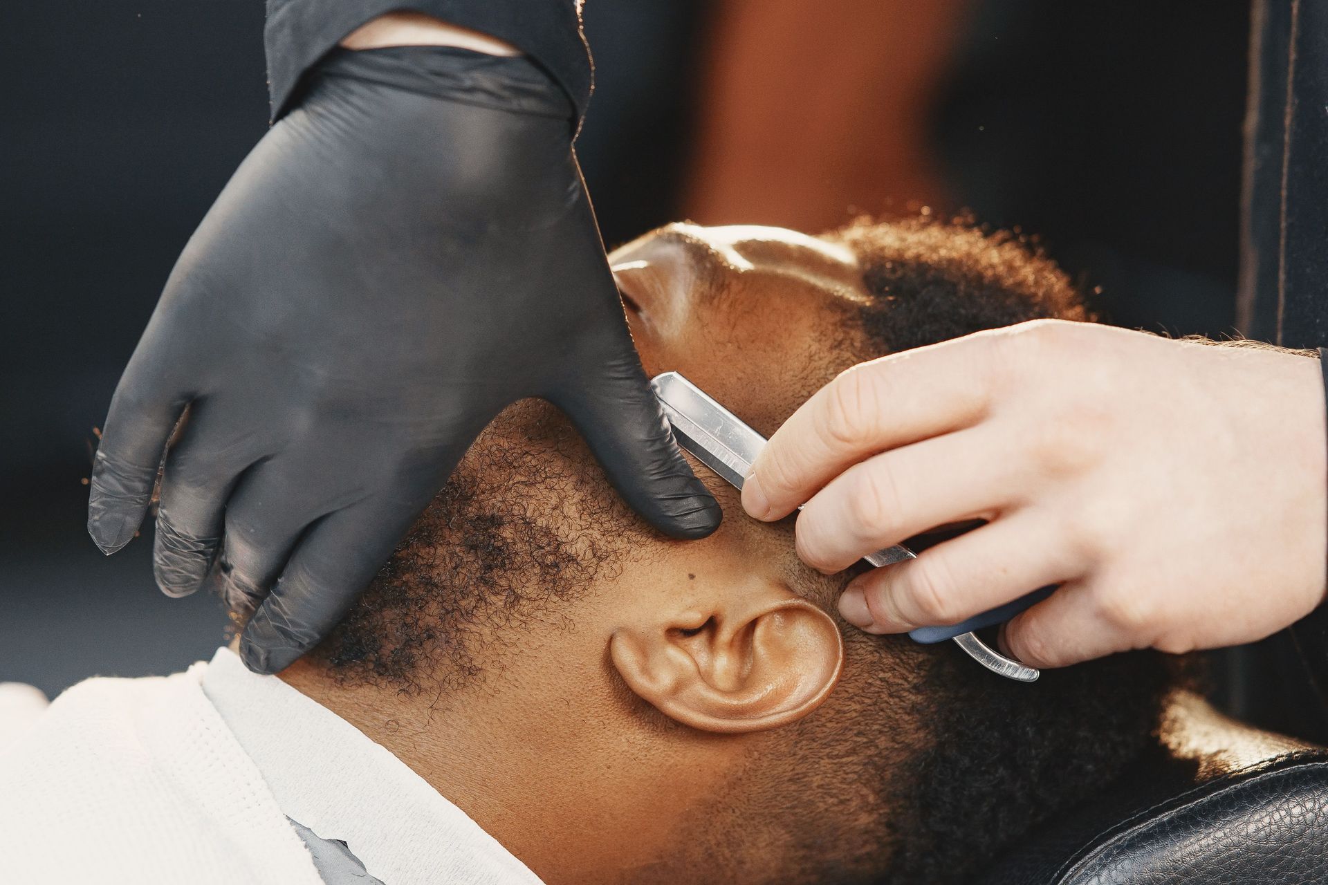 Barber skillfully using a razor to shave a client's beard with precision and care.